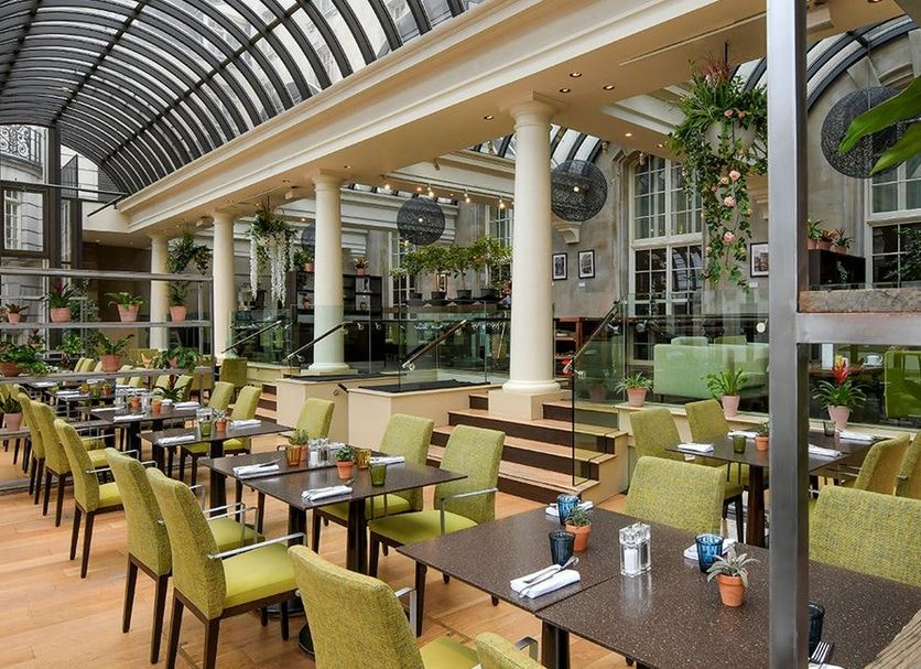 The Dilly, London: bright indoor courtyard restaurant with arched glass roof and green chairs