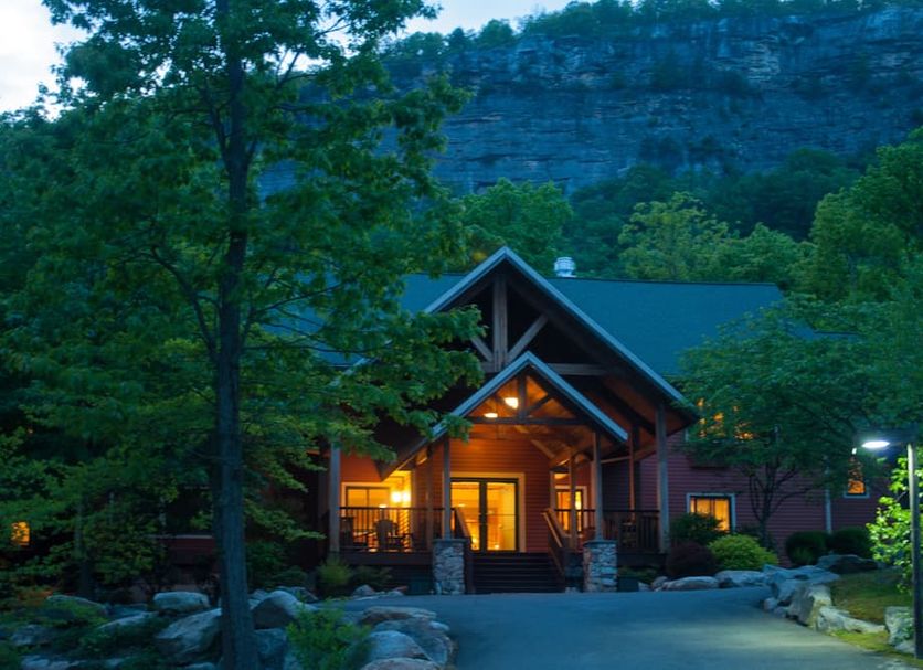 Minnewaska Lodge in Gardiner, rustic lodge exterior at dusk with glowing porch beneath rocky cliffs
