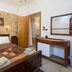 Spot Hotel Rhodes guest room with double bed, stone accent wall, desk, and open wardrobe