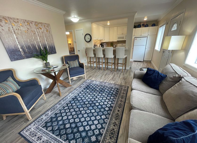 Arctic Fox Inn Anchorage living room with blue sofa, armchairs, rug, and kitchen bar stools
