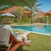Three Monkeys Villas in South Kuta with poolside loungers, palm trees, and tropical villas