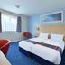 Travelodge Bedford Marston Moretaine room in Bedford with twin beds, window, and red chair