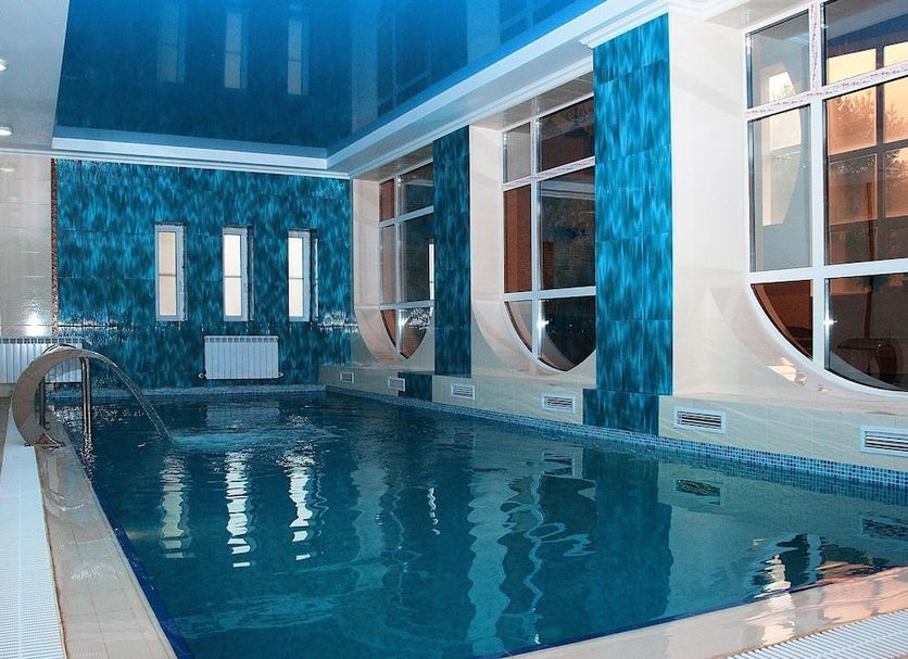 Indoor pool at Safir Hotel in Dushanbe with tall windows and blue mosaic walls