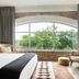 Arrive Memphis guest room with arched window, exposed brick, and view of trees in Memphis