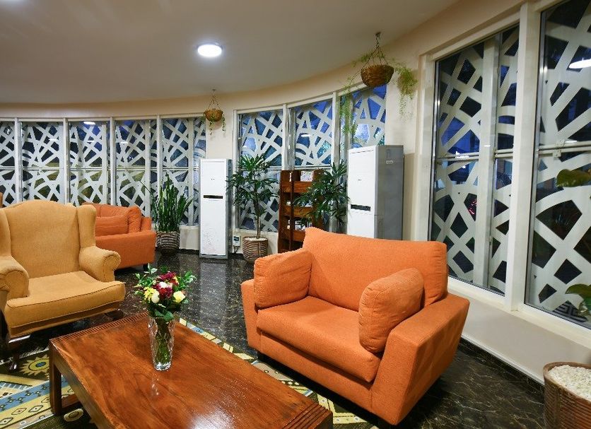 Arcadia Suite Kampala lounge with orange sofas, wooden coffee table and patterned lattice windows