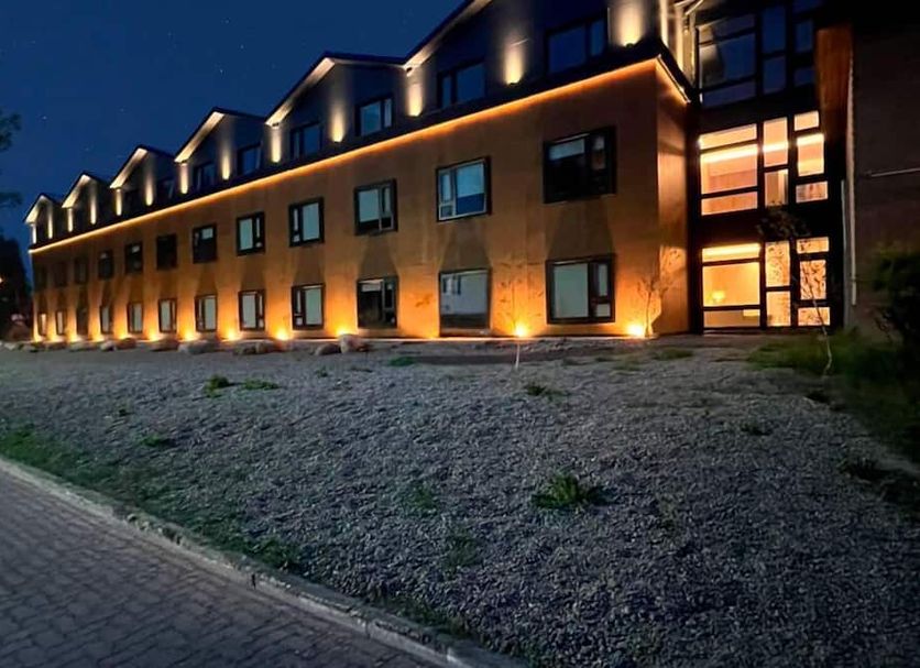 Hotel Bahia Redonda in El Calafate, lit exterior at dusk with gabled roof and stone landscaping