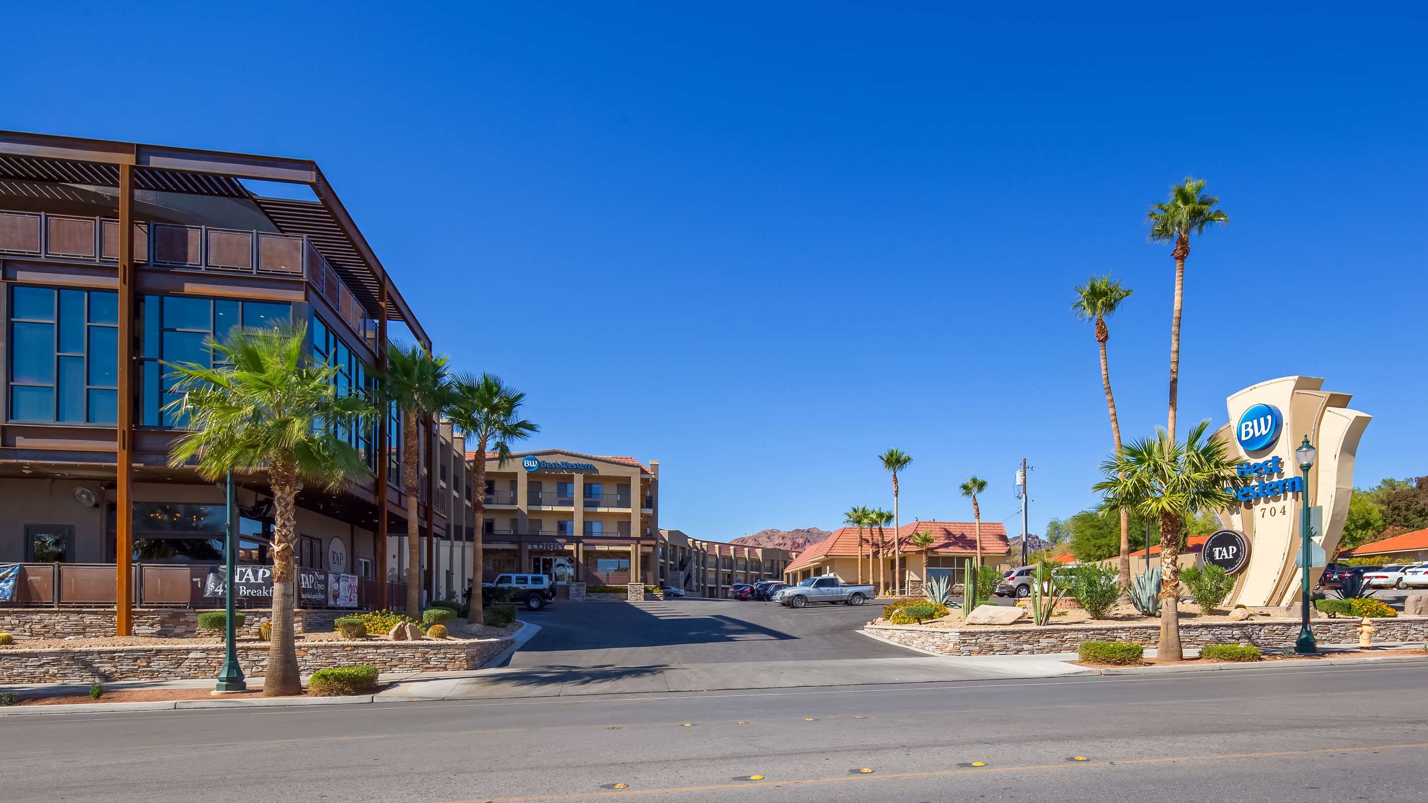 Best Western Hoover Dam Hotel in Boulder City with desert-style exterior, palm trees, and clear blue sky