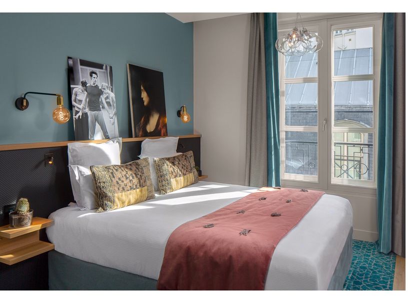 LYRIC Hotel Paris Opera guest room with king bed, teal walls and window view in Paris