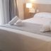 Hotel Victori in Es Castell room with a double bed, gray runner, rolled towels, and wall lamp