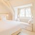 Château De Noirieux room in Briollay with a white bed and window seat by bright window