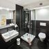 SL'otel Budget Bernburg bathroom with glass shower, wall-mounted sink, toilet and black tile walls