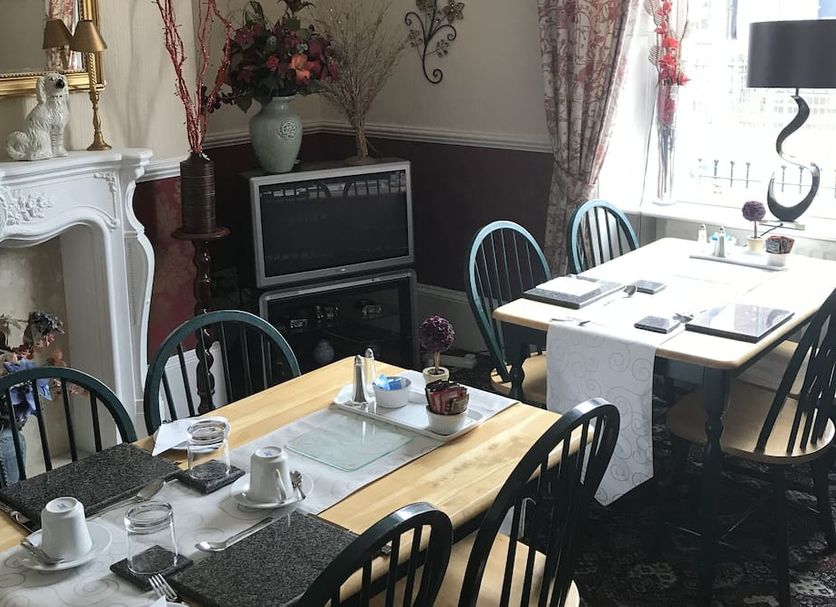 Brooklyn House in Carlisle dining room with set tables, ornate fireplace, and window seating