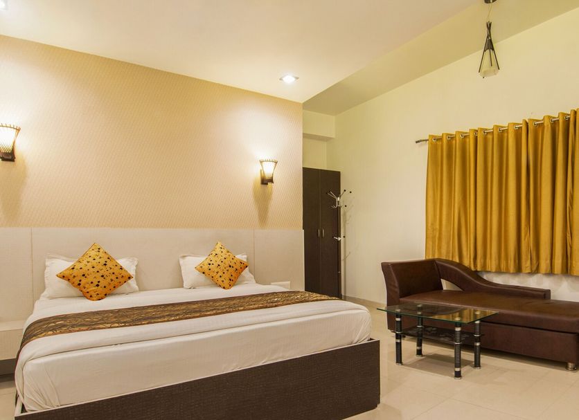 Hotel Metropolitan Jaipur guest room with king bed, sofa, and curtained window