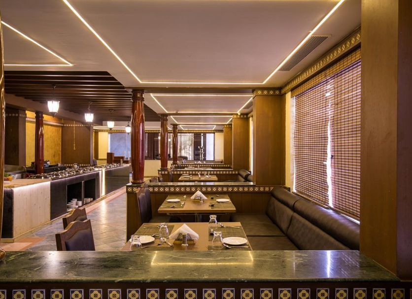 Hotel Grand Palace Chennai dining area with booth seating, wooden accents and large window blinds