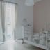 Sfumature Partenopee Naples room with white metal bed, sheer curtains, and pastel walls