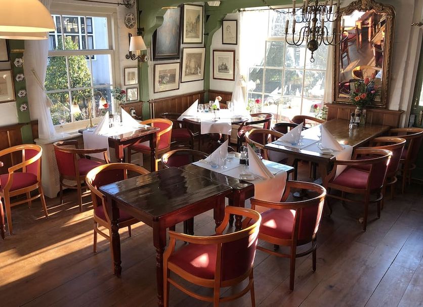 Hotel & Restaurant De Fortuna in Edam dining room with set tables, wooden chairs, and large windows