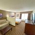 Sonesta Essential Hotels Overland Park guest room with sofa, bed, TV, and window light