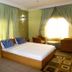 Junbic Apartment and Suites Abuja bedroom with king bed, green walls, sitting area and curtains
