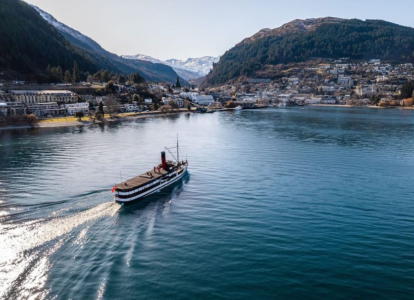 The Waterfront, Queenstown: boat on calm lake with mountain and town views