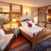 Pêche De Vigne & Spa in Rodern guest room with wooden bed, armchair, and patterned rug
