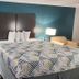 Motel 6 Crowley, La guest room with king bed, patterned bedspread, teal wall and bedside lamps