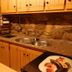 Albergue Rural Cal Picarol kitchen with stone walls, wood cabinets, sink and microwave in Àger