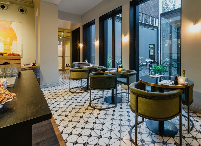 Hotel Monastère Maastricht in Maastricht dining area with tables, green chairs and floor-to-ceiling windows