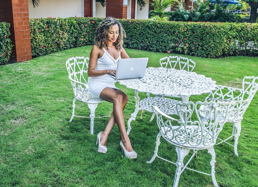 Hotel Jaragua Veracruz guest sitting at white garden table on lawn with laptop