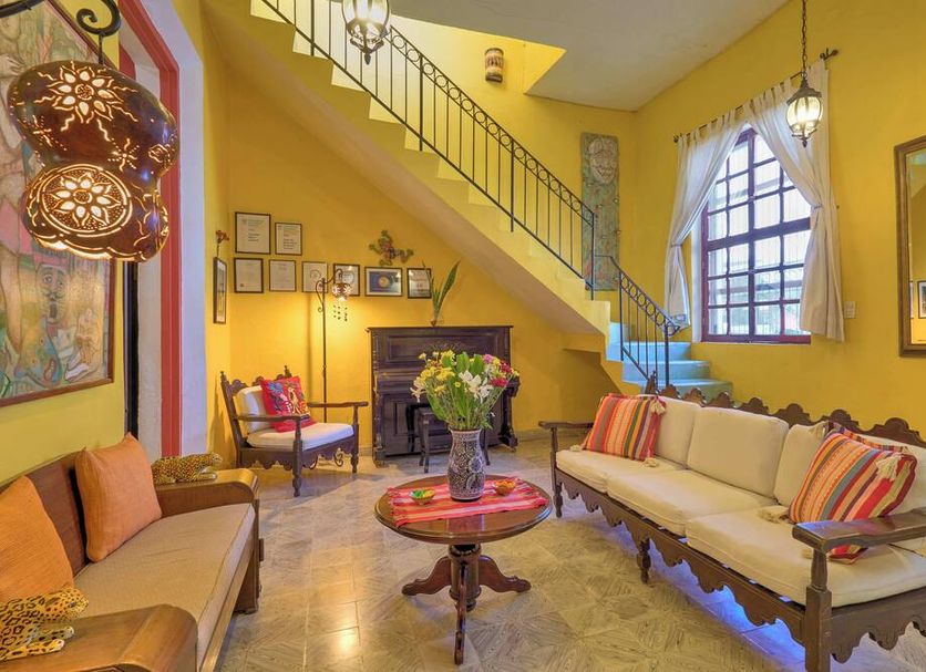 Casa Del Maya Bed & Breakfast in Mérida, colorful lounge with staircase, fireplace and arched window