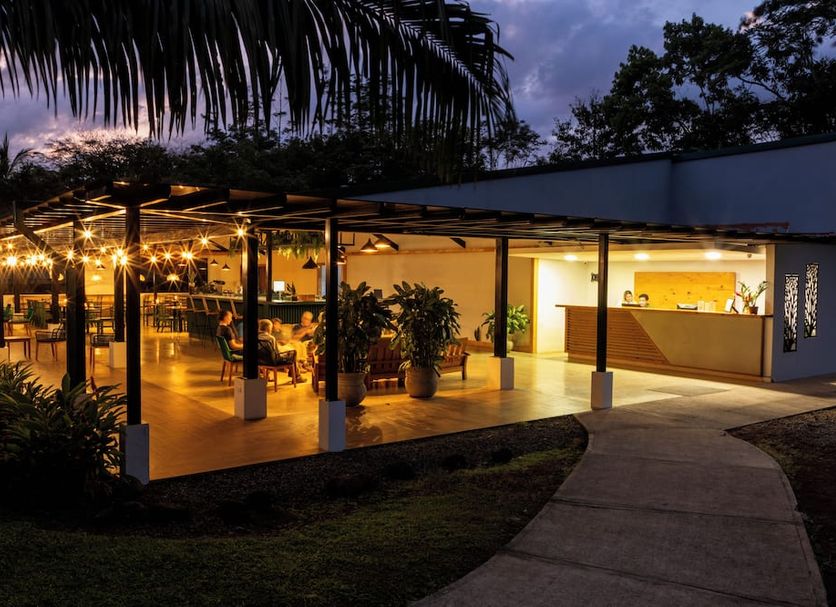 Natural Lodge Caño Negro in Caño Negro: illuminated open-air lodge terrace with palm trees at dusk