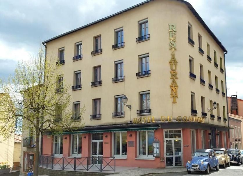 Hotel Du Commerce in Enval, 3-story corner hotel exterior with street parking