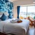 The Moana in Chatan guest room with ocean-inspired wall art, bed, and city view balcony
