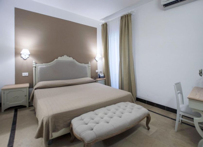 Hotel Gargallo in Siracusa guest room with double bed, tufted bench, nightstands and desk