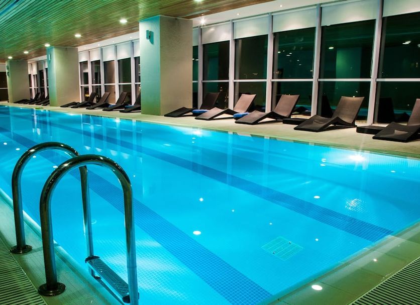 Indoor pool at The Landmark Hotel in Baku with lounge chairs and large windows
