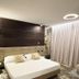 Iris Hotel Erbusco bedroom with queen bed, modern wall lighting and floor-to-ceiling curtains