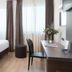 Hotel Omnia Noventa di Piave guest room with bed, desk, chair and sheer-curtained windows