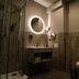 Hotel Civitas Sopron bathroom with walk-in shower, vessel sink, round mirror, and wall-mounted toilet
