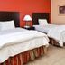La Bonita Inn & Suites - Mccamey room with two beds, bedside lamp and red accent wall in McCamey