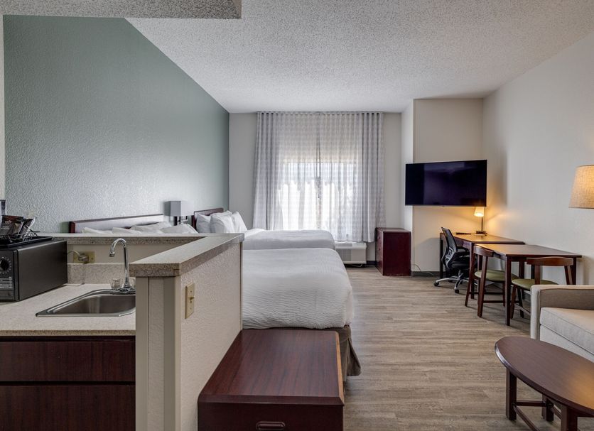 Mysuites Lawton guest room with bed, kitchenette, desk, wall-mounted TV and seating area in Lawton