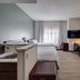Mysuites Lawton guest room with bed, kitchenette, desk, wall-mounted TV and seating area in Lawton