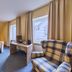 Arador City Hotel in Bad Oeynhausen guest room with desk, armchair, plaid chair and two windows