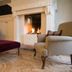 Country House Duinhof in De Haan: cozy lounge with fireplace, armchairs and patterned rug