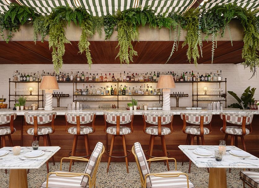 Holloway House West Hollywood bar with marble tables, wicker chairs and hanging greenery