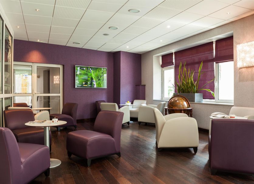 Les Thermes de l'Avenue in Dax lounge with purple seating, wall TV, and large windows