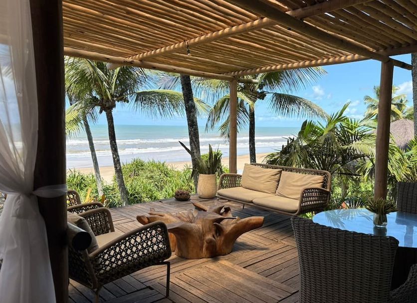 Pousada Morro dos Navegantes in Ilhéus with ocean-view patio, palm trees, and seating under a thatched roof