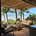 Pousada Morro dos Navegantes in Ilhéus with ocean-view patio, palm trees, and seating under a thatched roof