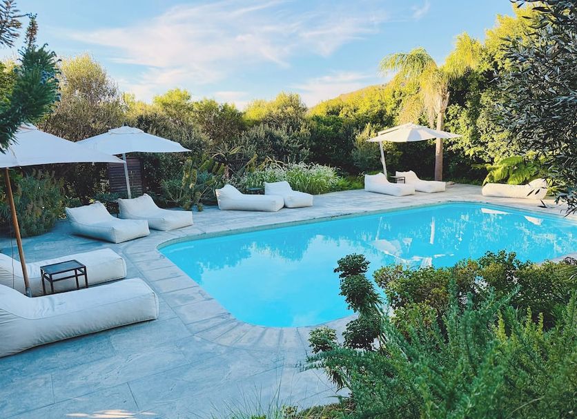 Sovn Experience+Lifestyle Cape Town poolside lounge with umbrellas, daybeds and lush garden