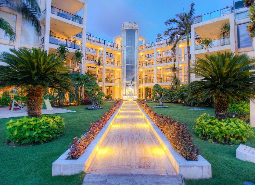 Furamaxclusive Ocean Beach Seminyak Bali courtyard walkway with lit poolside gardens in Kuta