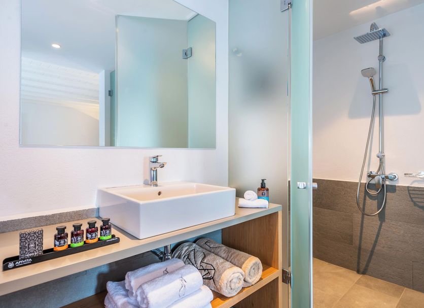 Dreambox Mykonos Suites bathroom with sink, glass shower, and neatly folded towels in Mykonos