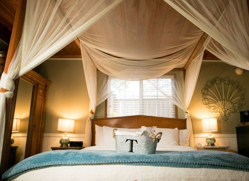 J Patrick Inn in Cambria bedroom with four-poster canopy bed, blue quilt, and window shutters